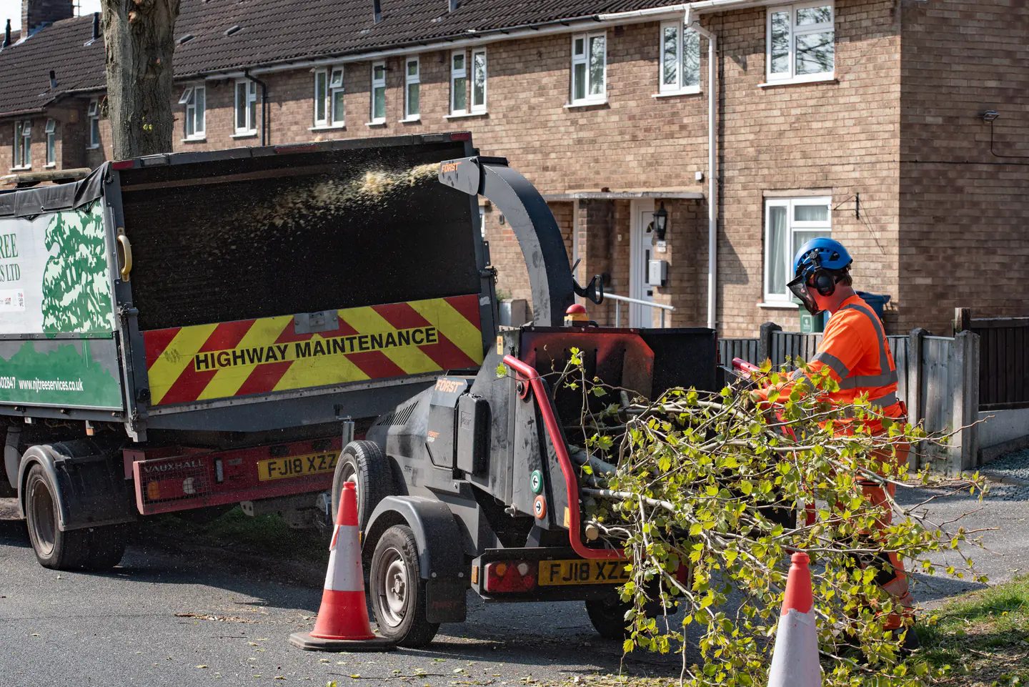 Branded N&J Tree Services vehicle, chipper and operative working on a housing estate